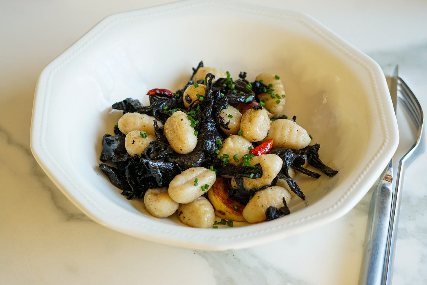 Gnocchi con trompetas de la muerte y guindilla